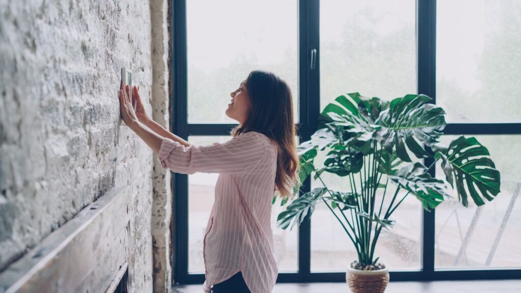 Person adjusting a wall thermostat in a bright modern office interior