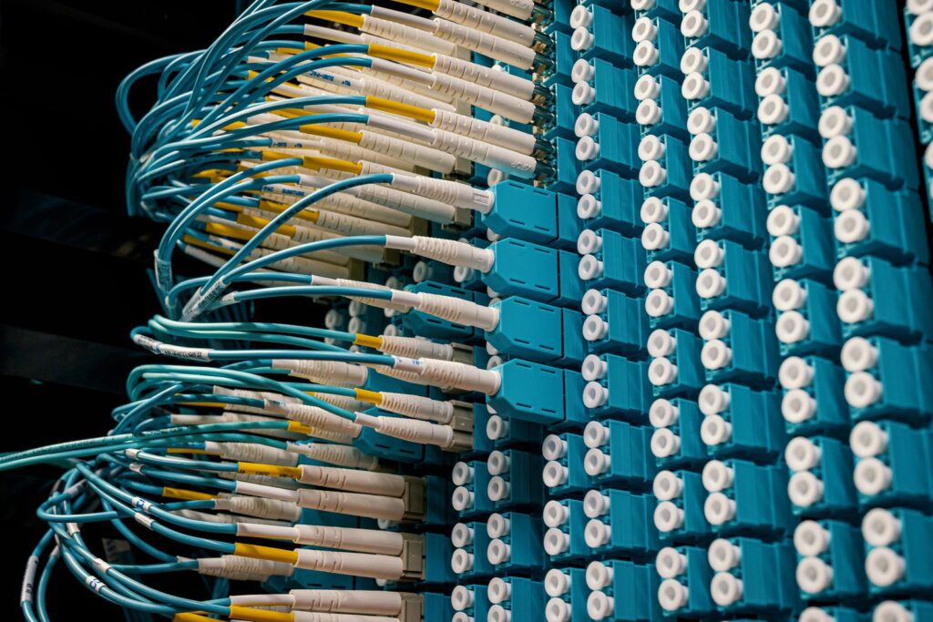 Fiber optic patch cables plugged into a blue network patch panel