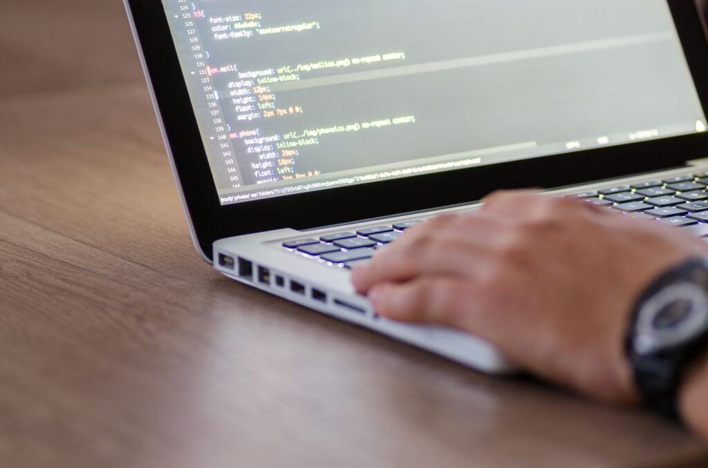 Web developer editing website code on a laptop keyboard