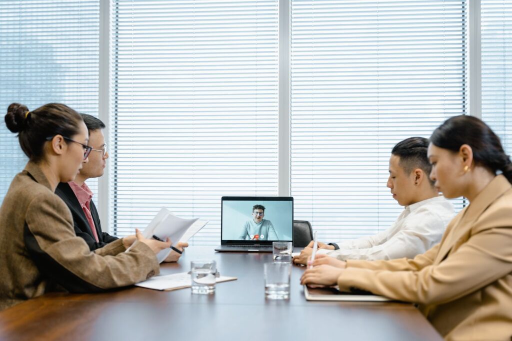 Small business team in a conference room on a video call with a remote colleague