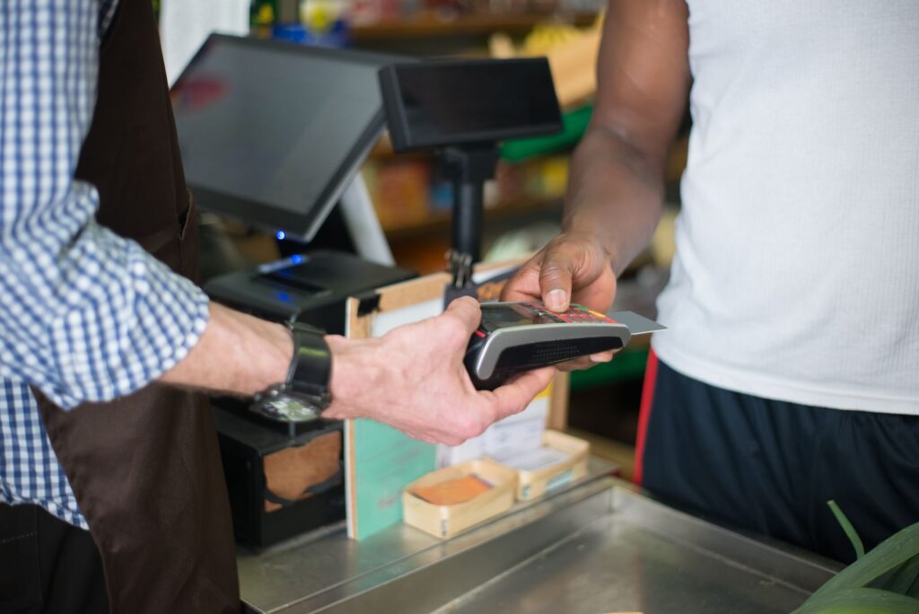 Merchant taking a contactless card payment on a countertop POS terminal in a store