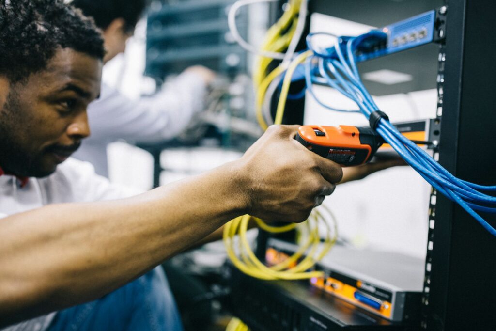 Technicians working on network cabling inside a business server rack