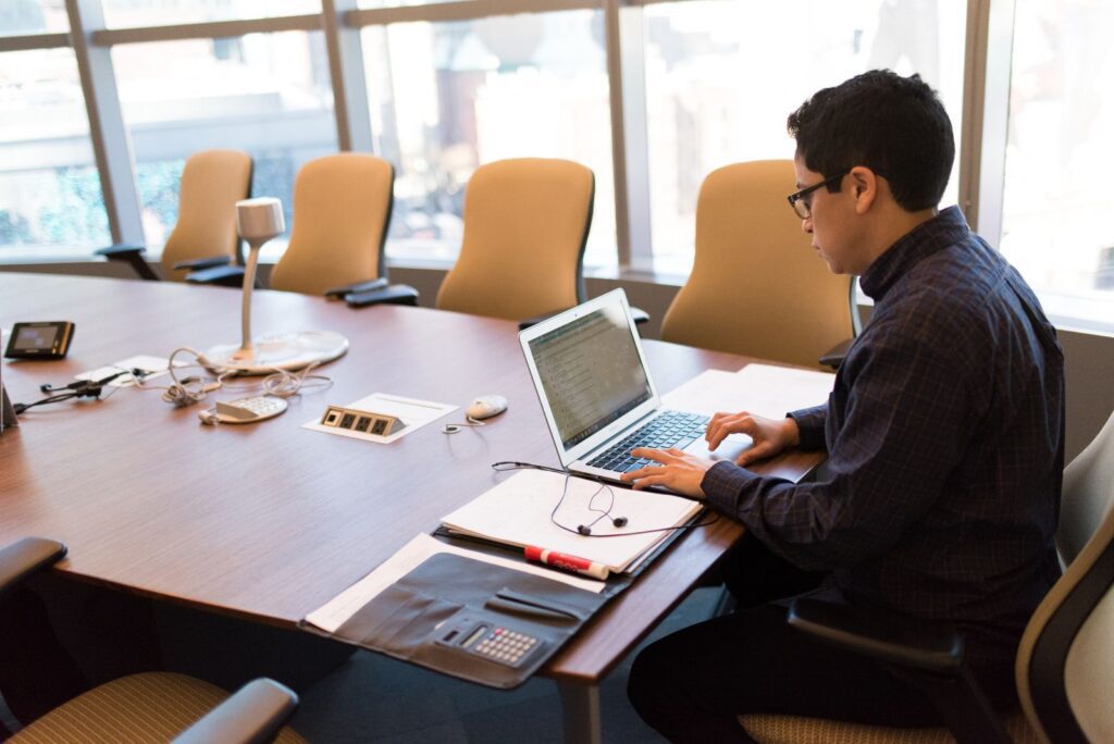 Employee working on a laptop at an office conference table