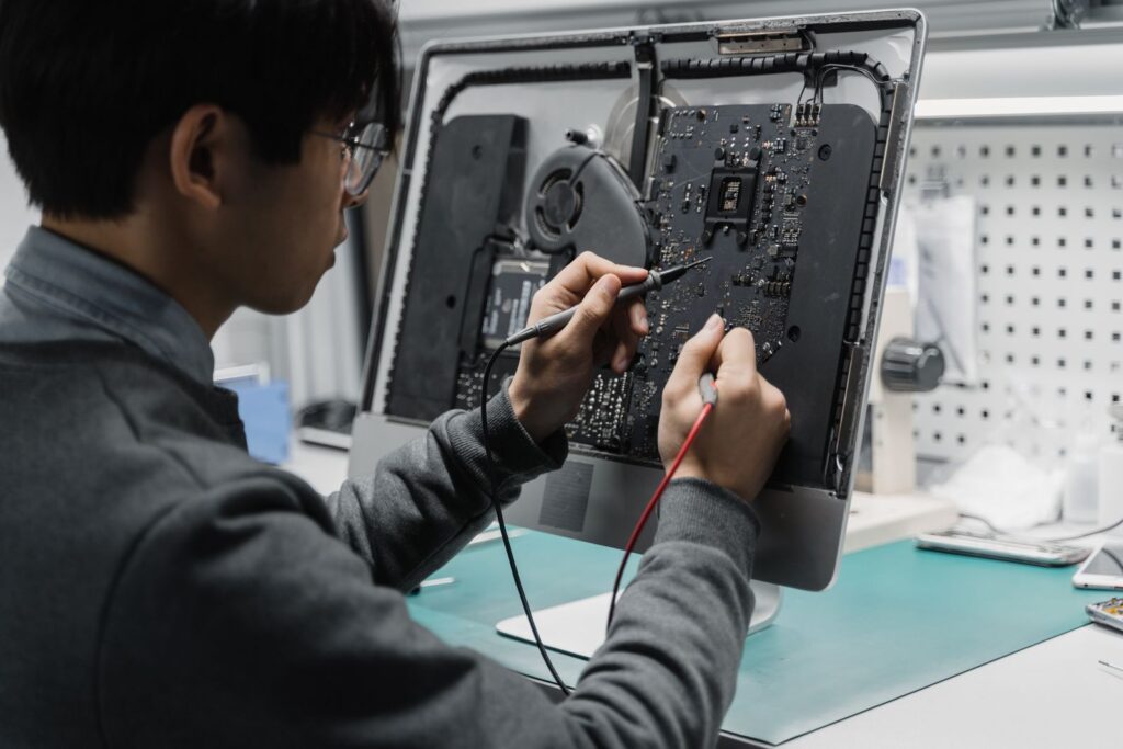 Computer repair technician testing a desktop computer motherboard at a workbench