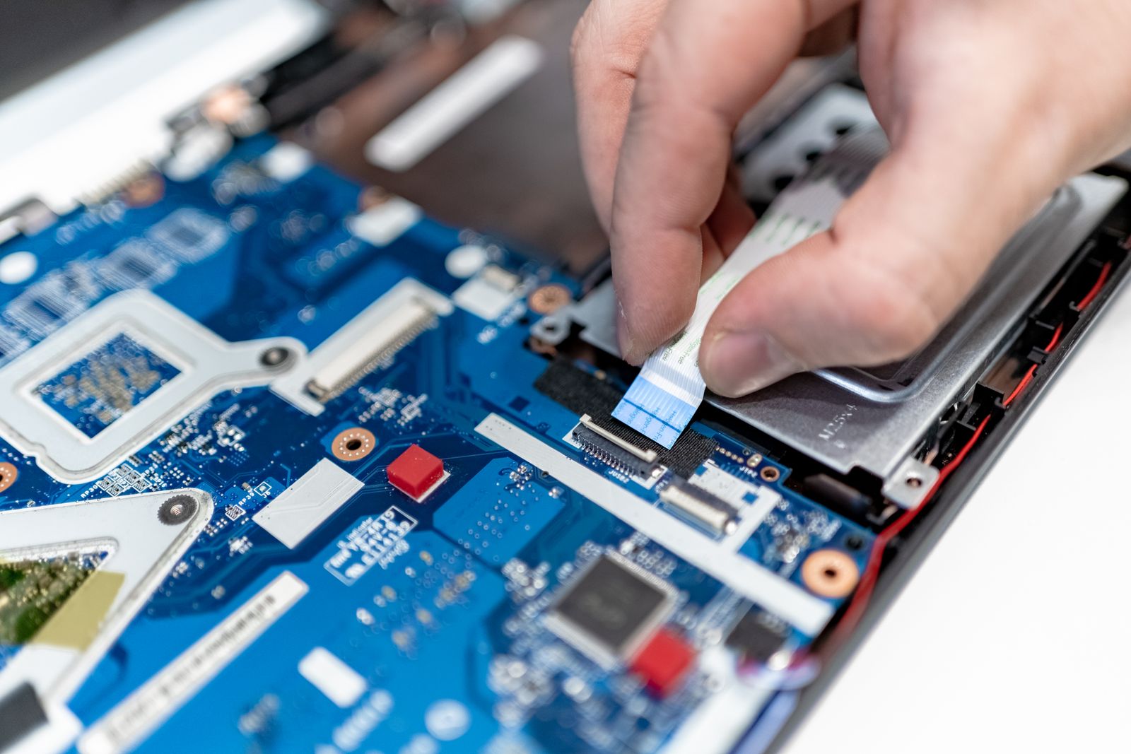 Technician reconnecting a ribbon cable during a laptop computer repair
