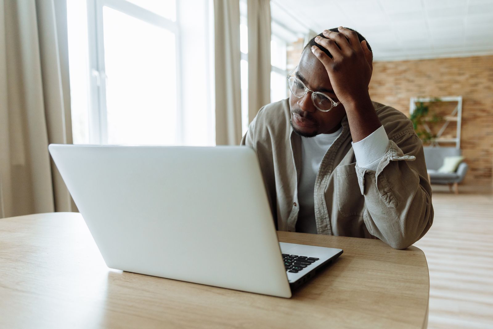Frustrated man at home staring at a laptop that keeps freezing