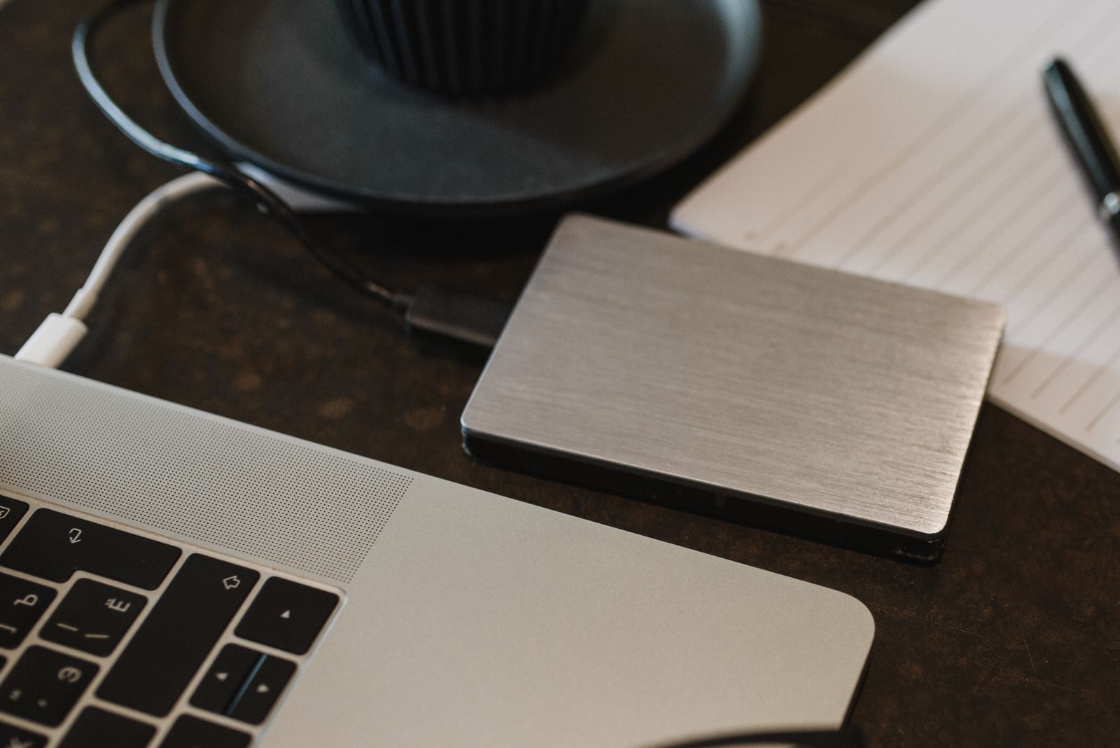 External hard drive connected to a laptop by USB cable on a desk