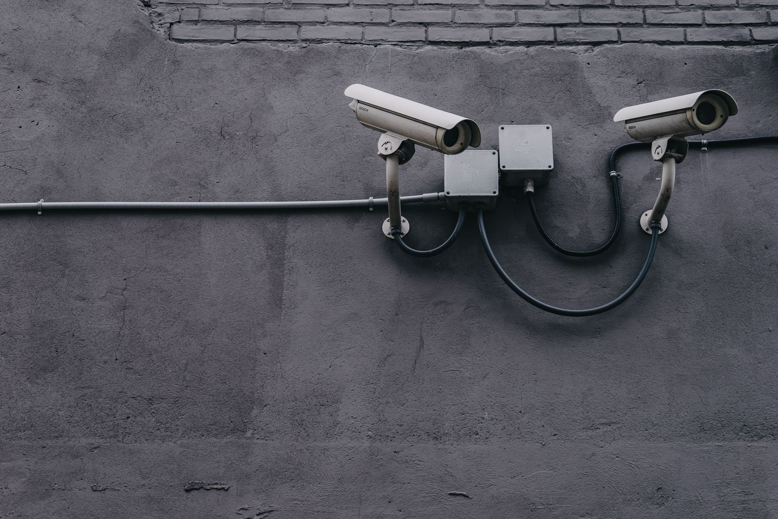 Two wired PoE security cameras mounted on a wall with cable conduit