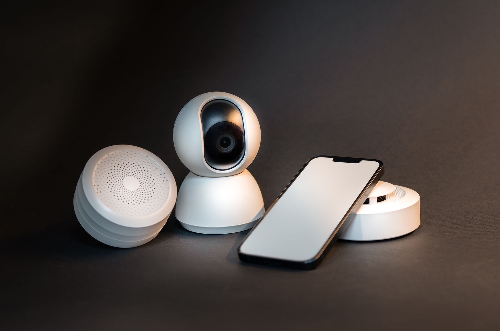 Smart home camera, speaker, sensor and phone on a dark background