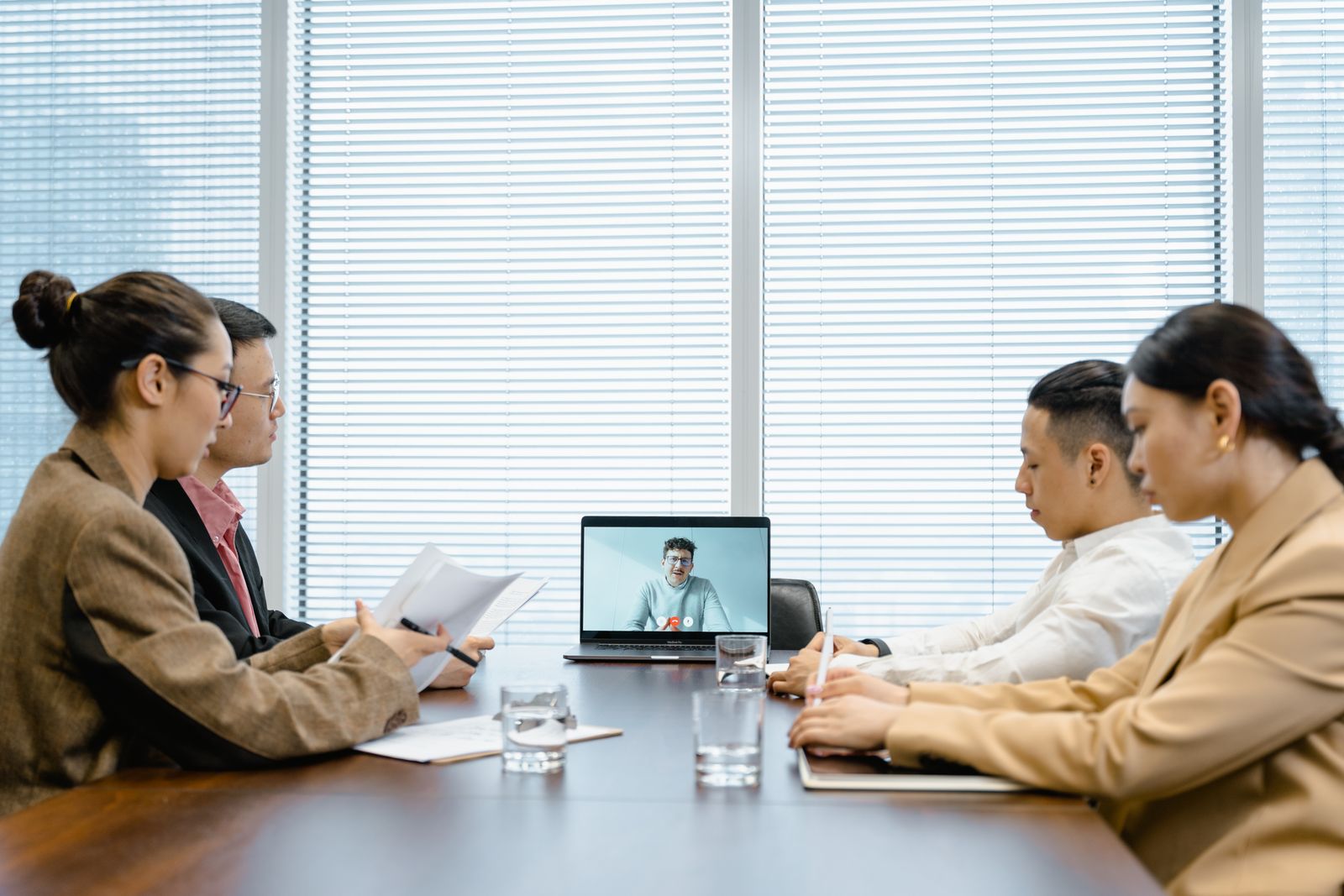 Small business team in a conference room on a video call with a remote colleague