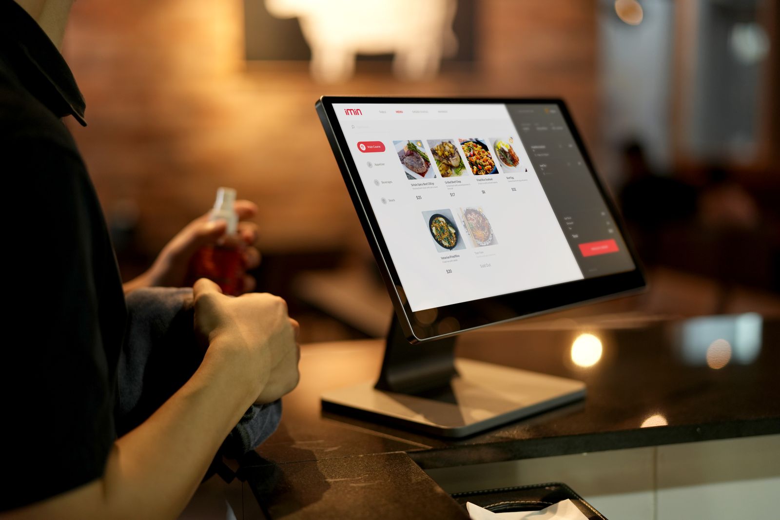 Restaurant staff member using a point of sale terminal at a counter