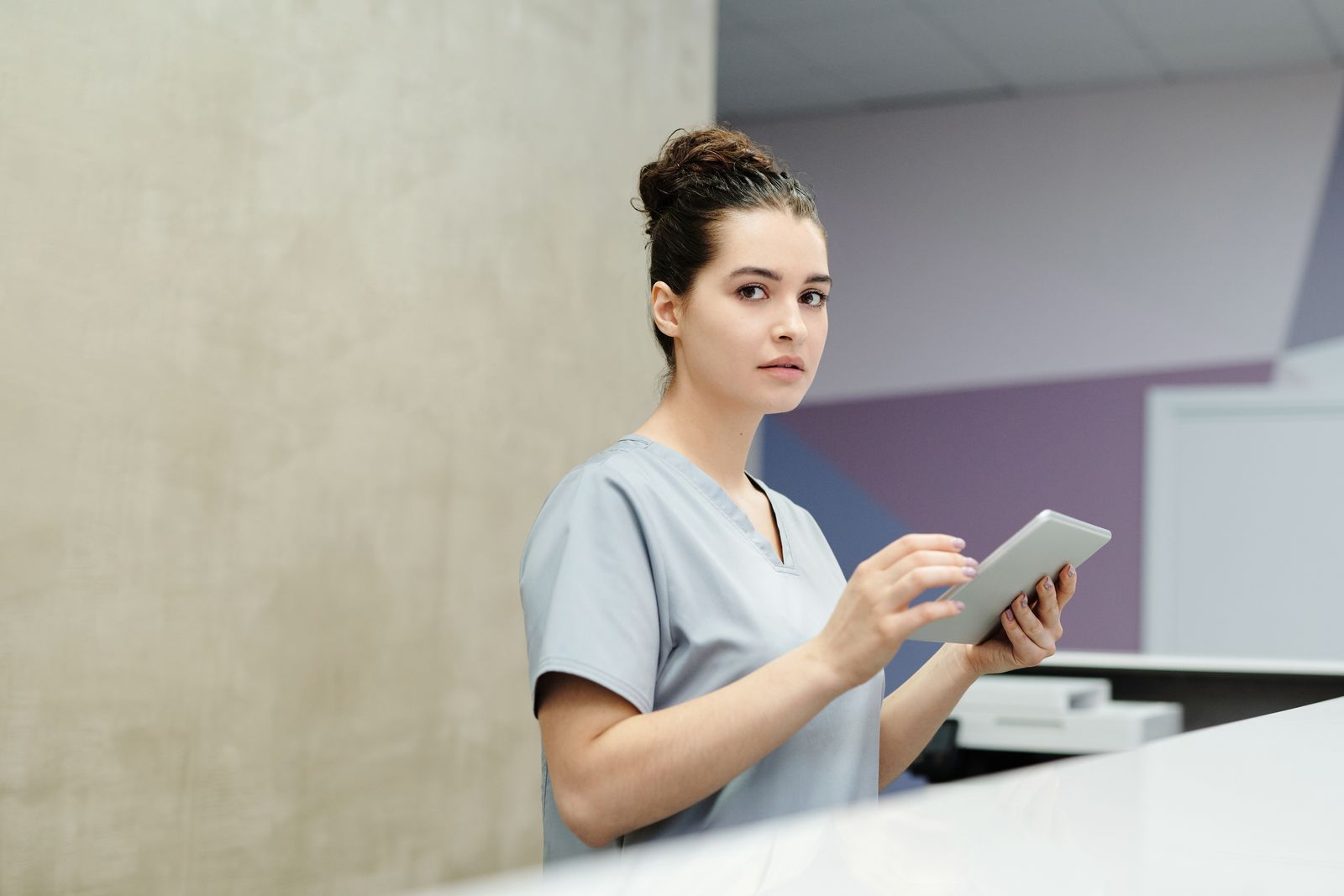 Receptionist using a tablet at a modern office front desk